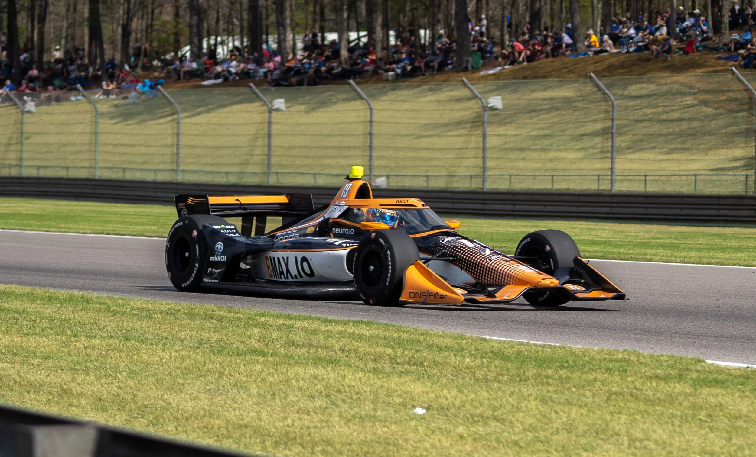Race car driving on a track with a crowd of spectators in the background.