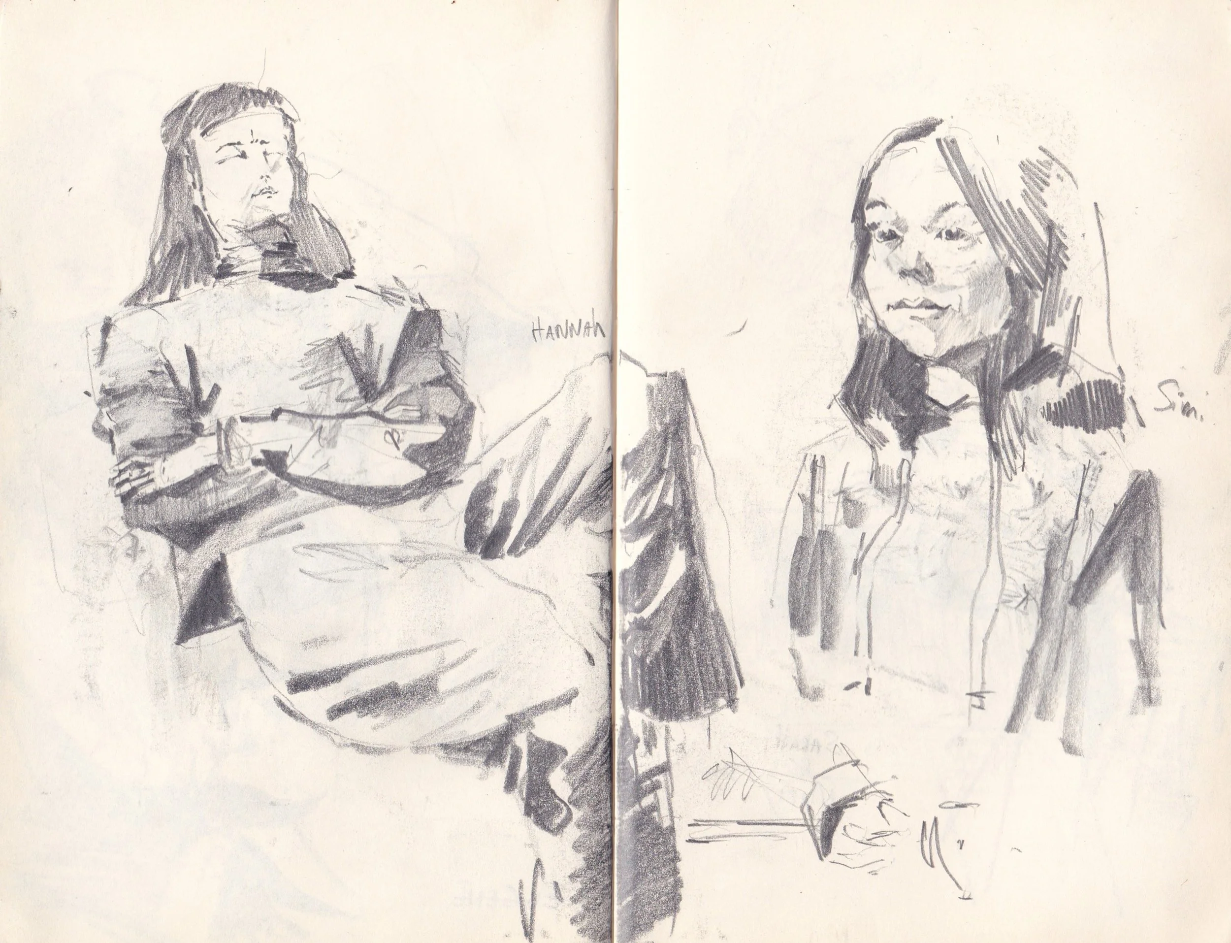 Two black and white sketch portraits of women on two pages of a notebook. The left woman has long hair and is seated, looking sideways with arms crossed. The right woman has long hair and is facing forward with a slight smile. The sketches are rough 
