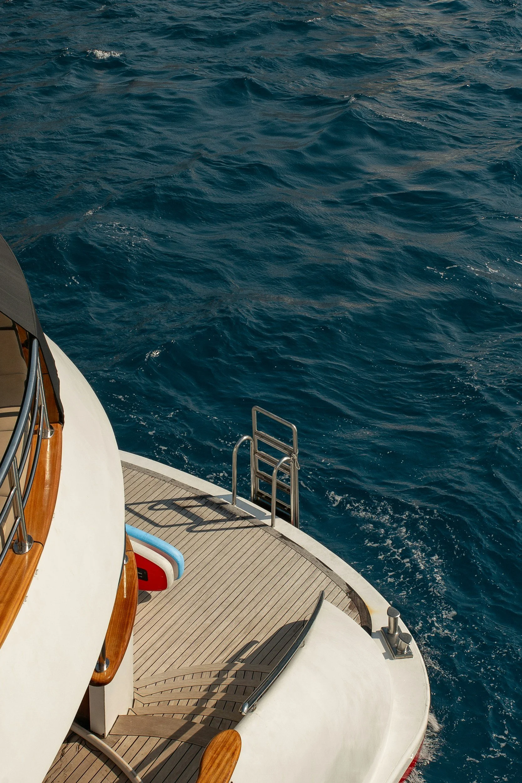 View of the ocean from the deck of a boat, showing water with small waves and part of the boat's deck and railings.