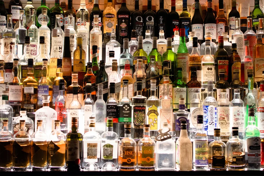 A fully stocked liquor bottle wall behind a bar. Tobacco License