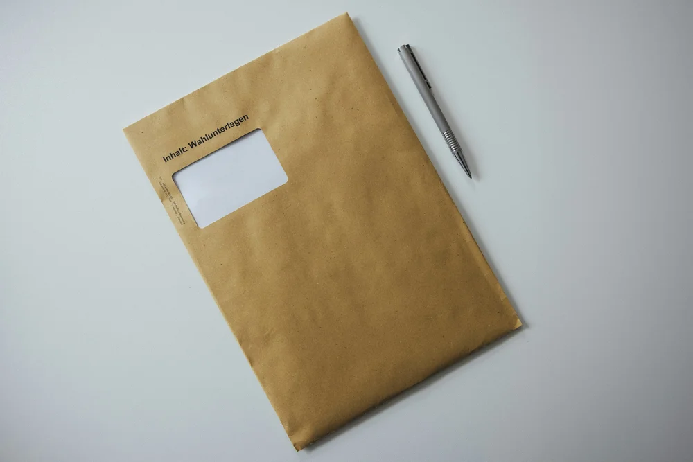 A sealed envelope with a pen for filing paperwork. Sales and Use Permit Bond