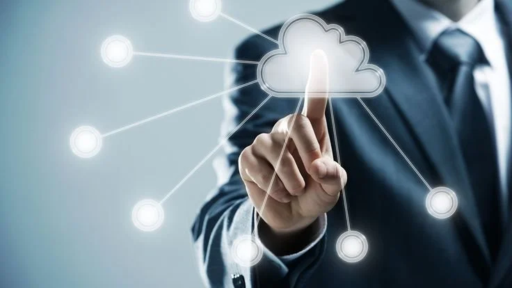 A person in a business suit touching a digital cloud icon with a finger, with connected nodes around it, representing cloud computing or network connectivity.