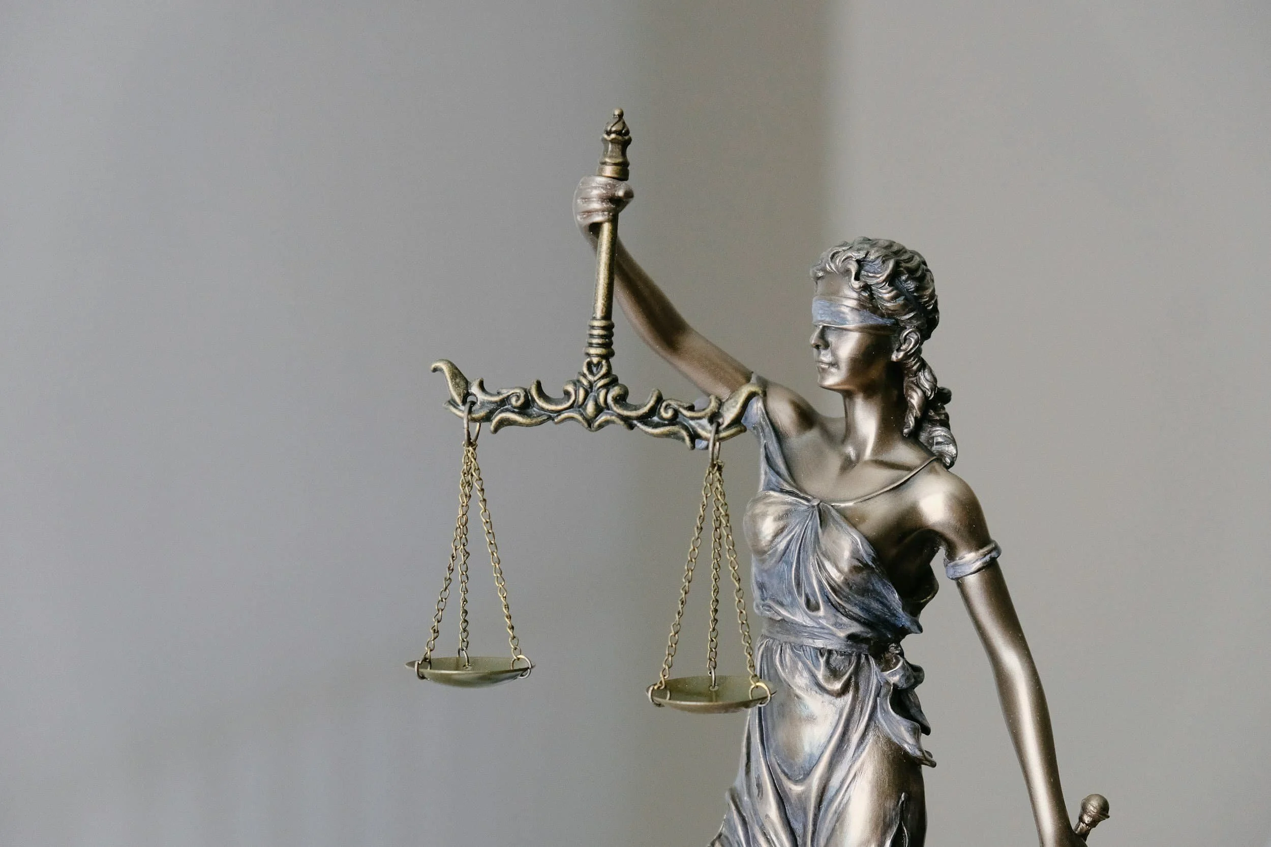 A metallic sculpture of Lady Justice holding scales in her left hand and a sword in her right hand, with her eyes blindfolded.