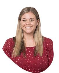 A woman with long blonde hair, smiling, wearing a red polka dot top, against a white background.