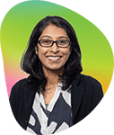 Portrait of a woman with glasses smiling, wearing a dark blazer and patterned scarf, against a colorful gradient background