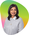 Portrait of a smiling woman with dark hair, wearing a gray sweater and necklace, against a colorful gradient background.