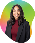 A woman with long dark hair smiling, wearing a black blazer and maroon top, standing against a colorful gradient background.