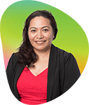 Portrait of a woman with dark hair wearing a black blazer and red top, smiling against a colorful gradient background.