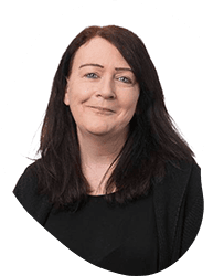 A woman with dark hair and a light skin tone, wearing a black top and blazer, smiling slightly against a plain white background.