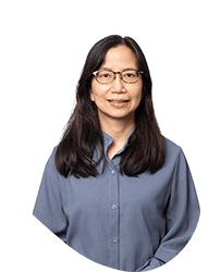 A woman with long dark hair wearing glasses and a blue button-up shirt, standing against a white circular background.