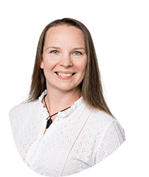 A smiling woman with long brown hair wearing a white blouse against a white background with a black circle design.