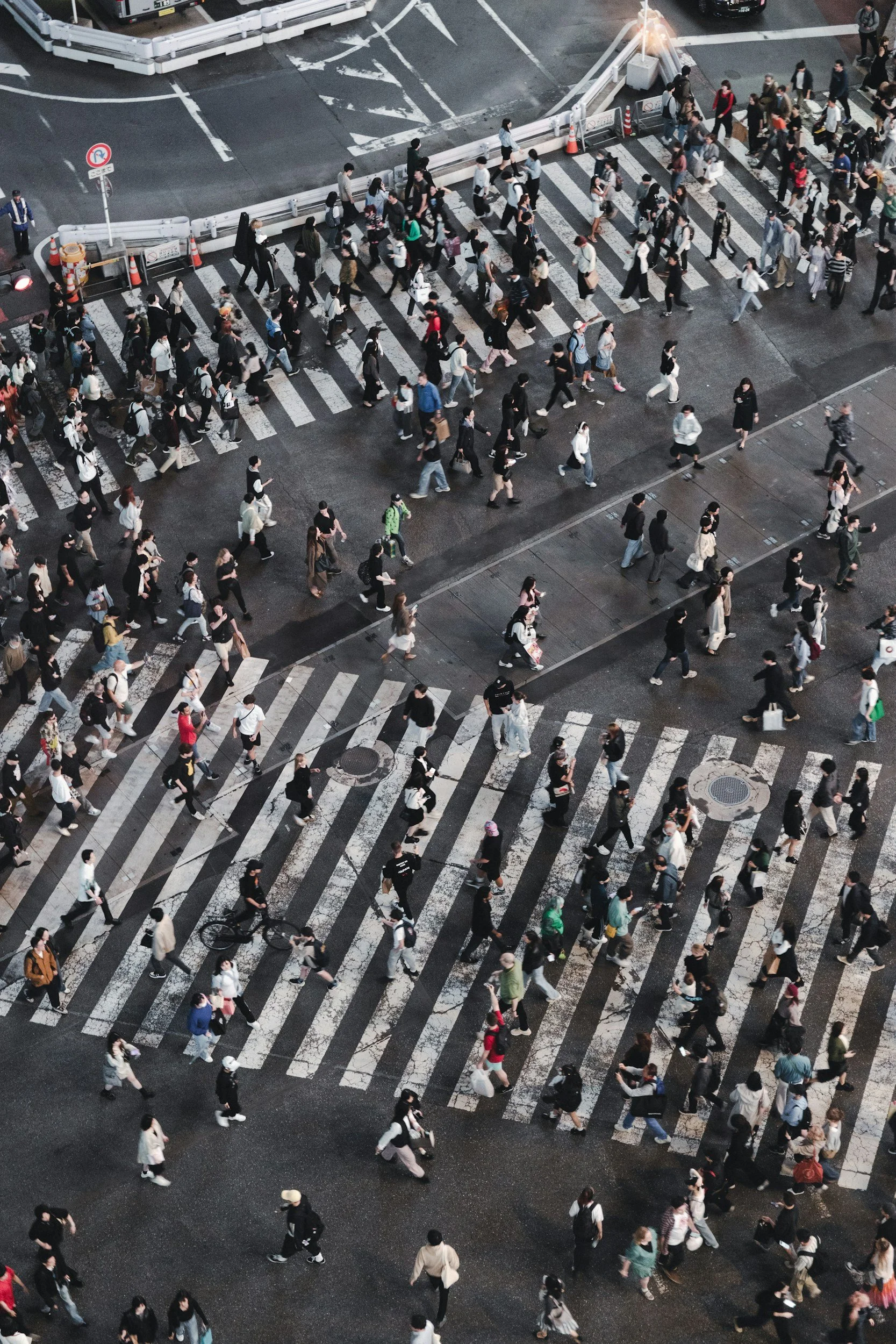 Aerial view of a busy city crosswalk with many pedestrians crossing the street at night.