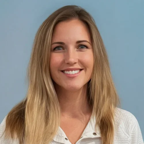 A smiling woman with long blond hair wearing a white top against a light blue background.