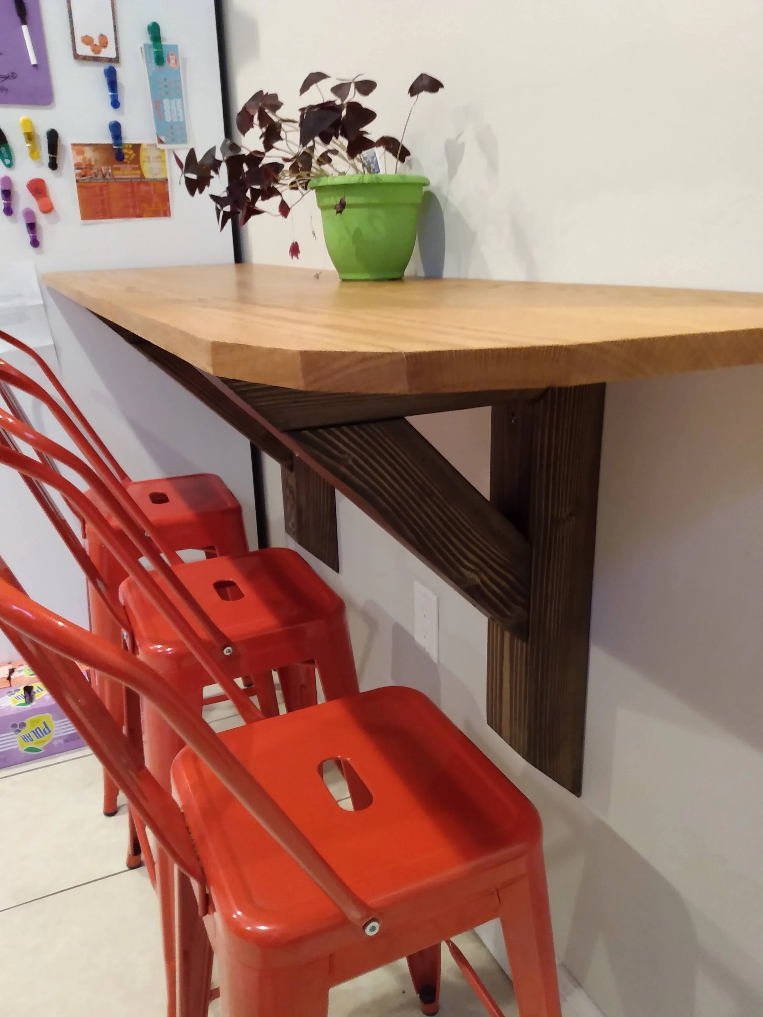 Red chairs lined up against a wall with a wooden table topped with a green potted plant.