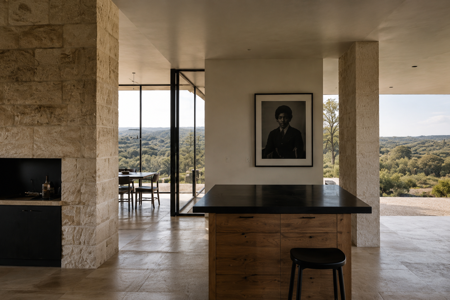 Minimal kitchen and dining area with limestone walls, wood cabinetry, and floor-to-ceiling windows overlooking the hills.