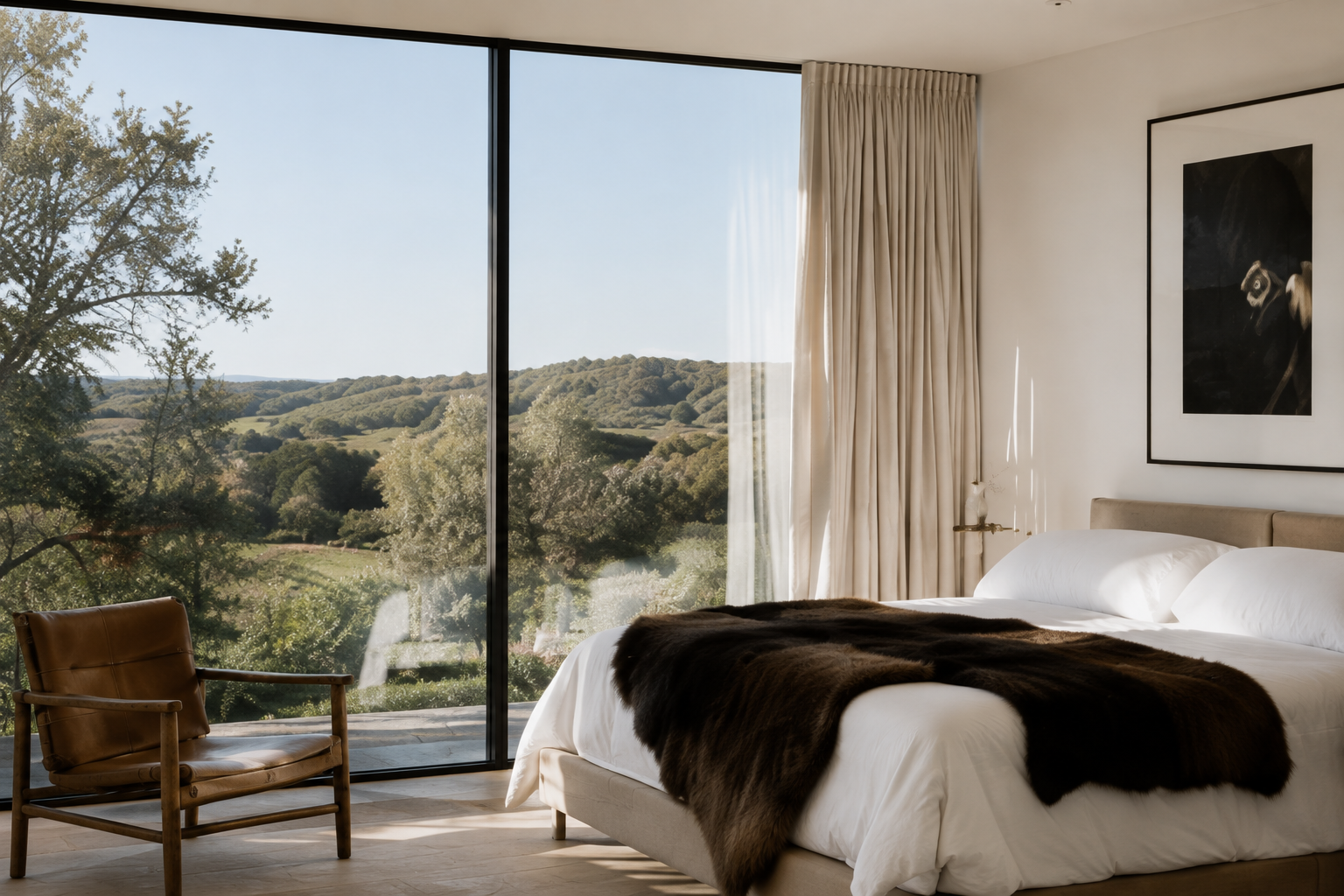 Bedroom with floor-to-ceiling windows, white bedding, dark hide throw, and expansive Hill Country views.