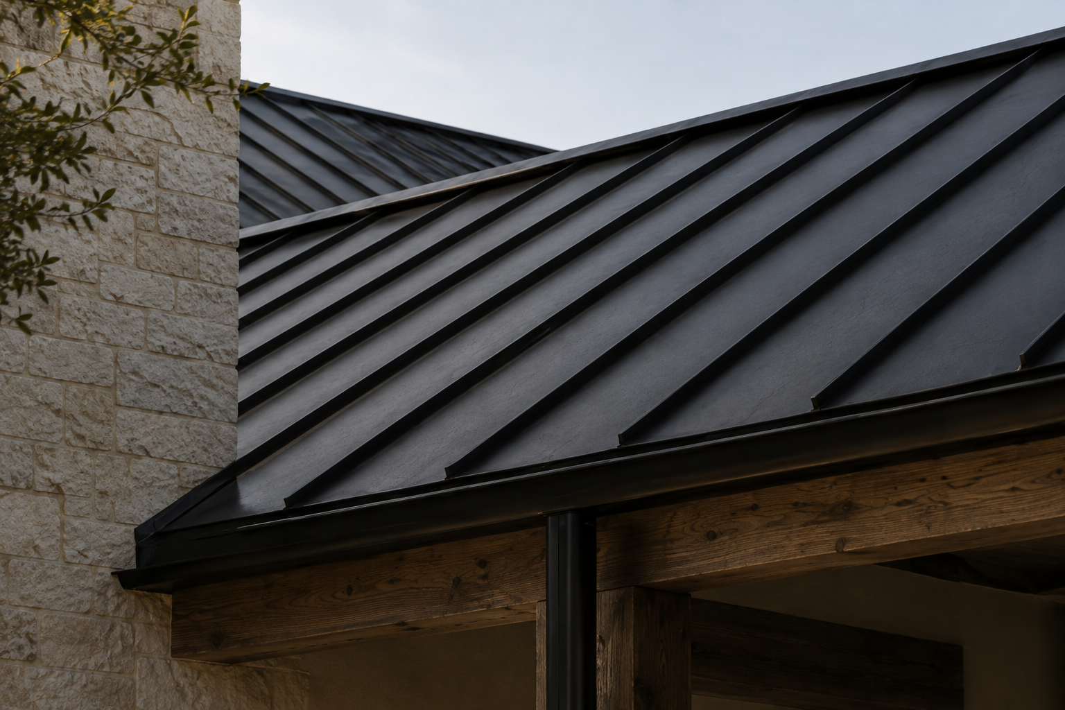 Black standing-seam metal roof meeting limestone walls and exposed wood construction.