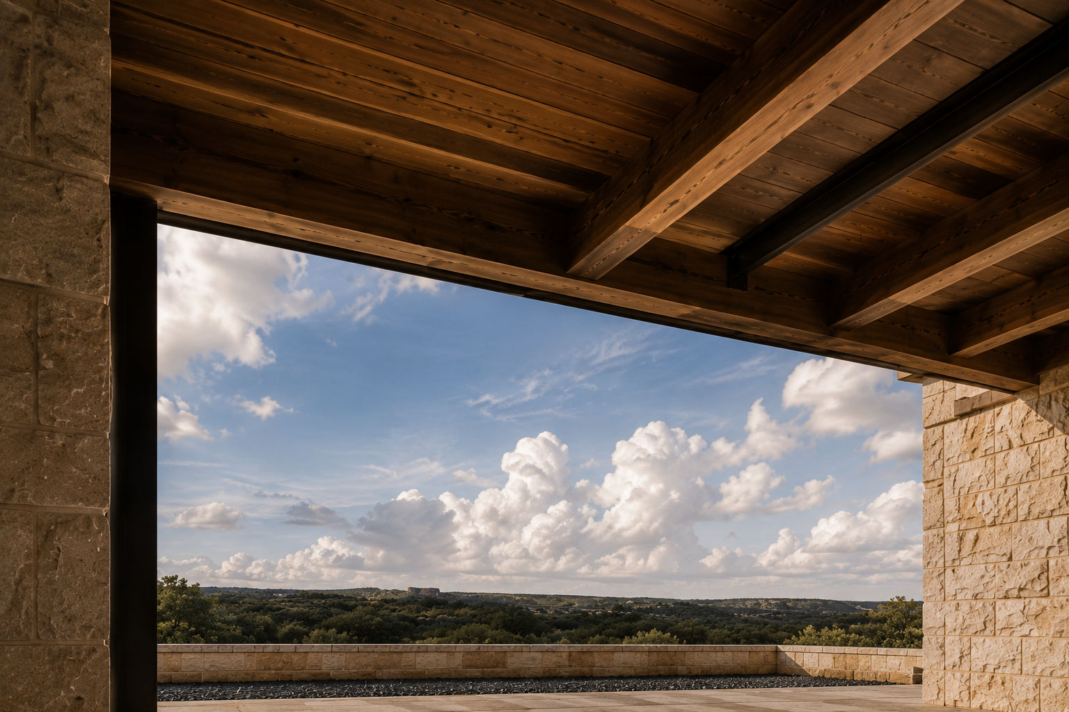 Covered terrace beneath a wood-beamed roof overlooking open Hill Country landscape and clouds.
