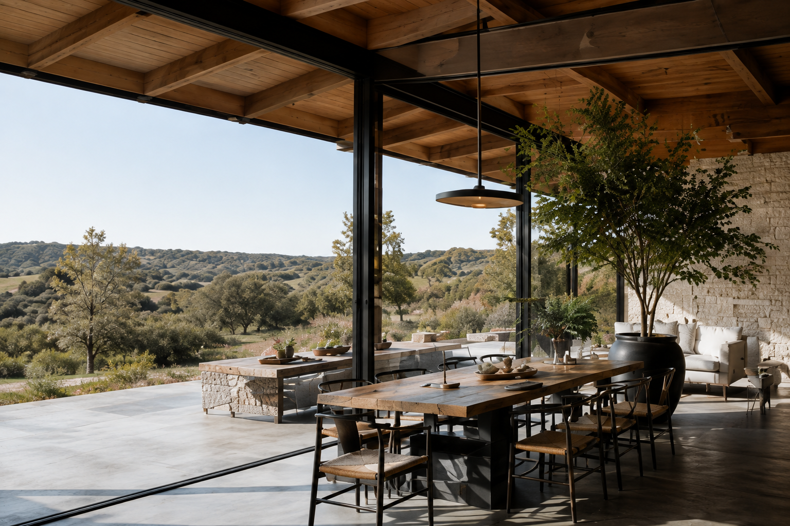Dining area with black steel windows, wood ceiling, long table, and doors opening to the landscape.