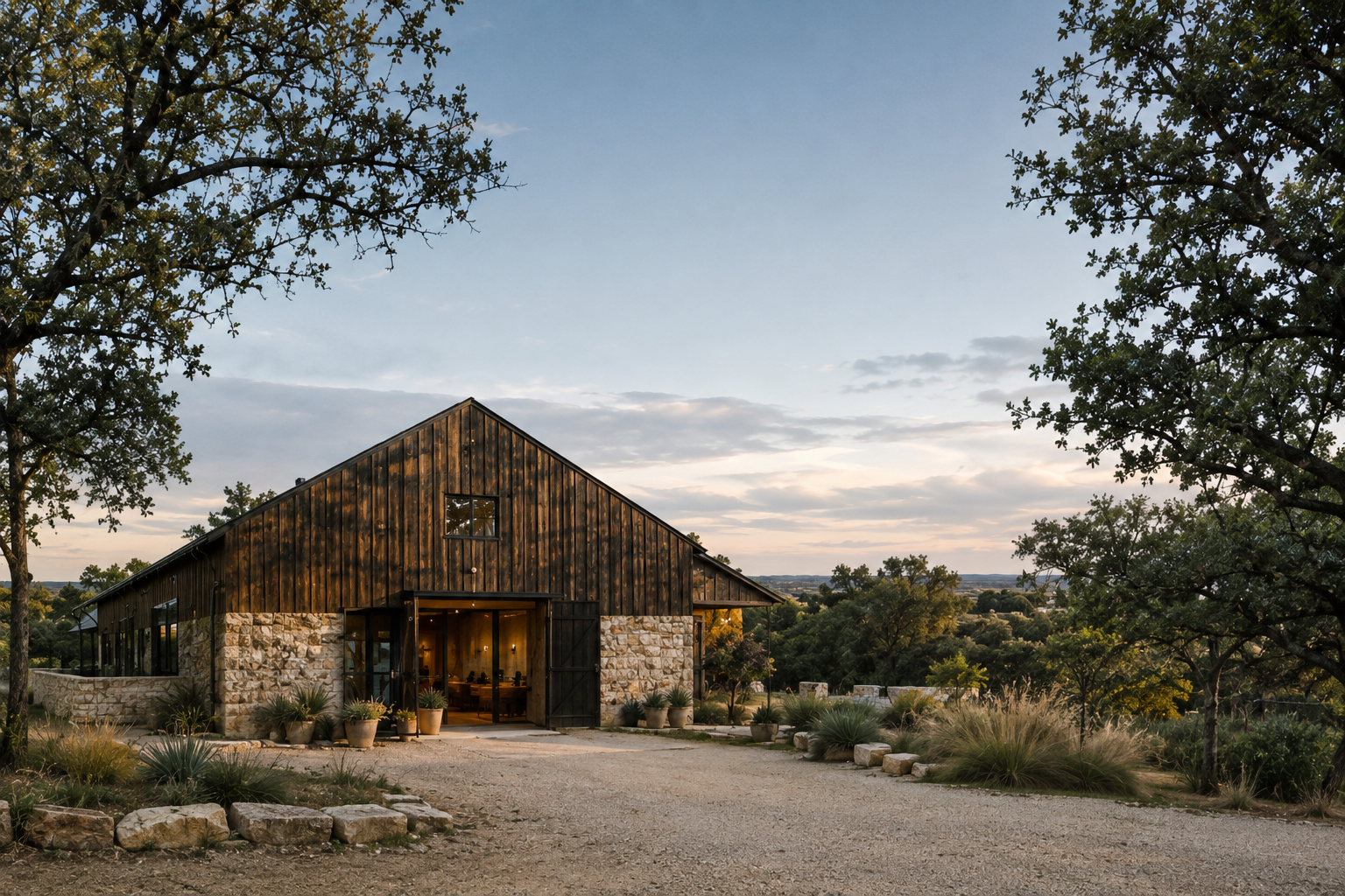 Dark timber-clad residence with a pitched roof surrounded by native grasses and oak trees.