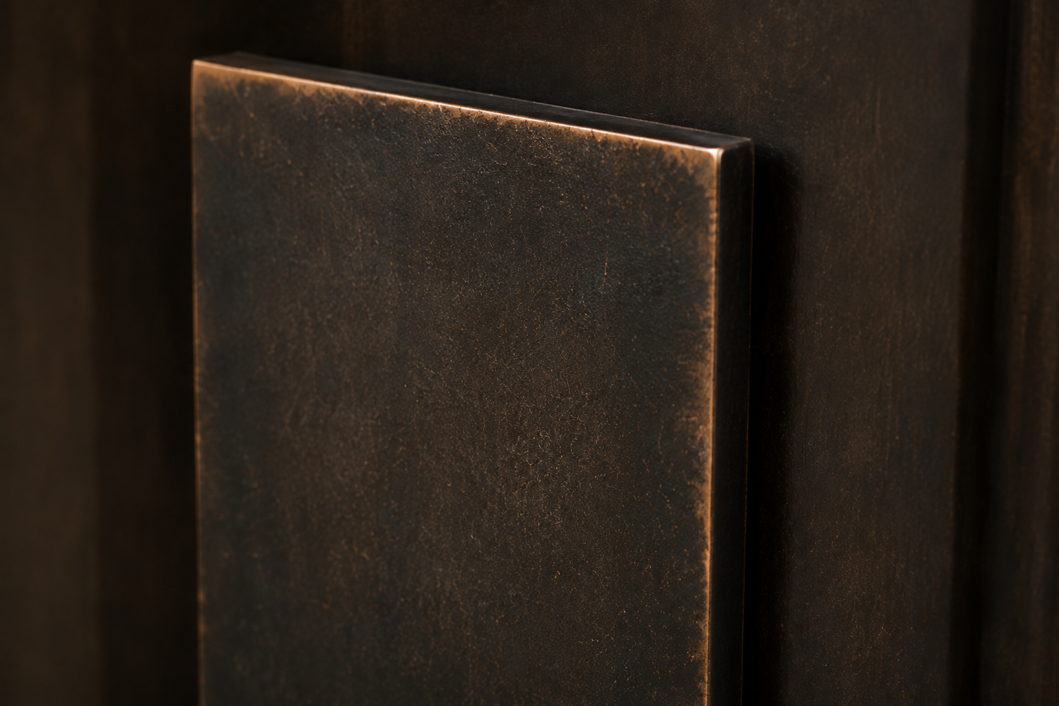 Minimal dark metal wall sconce casting warm light against a textured wall.