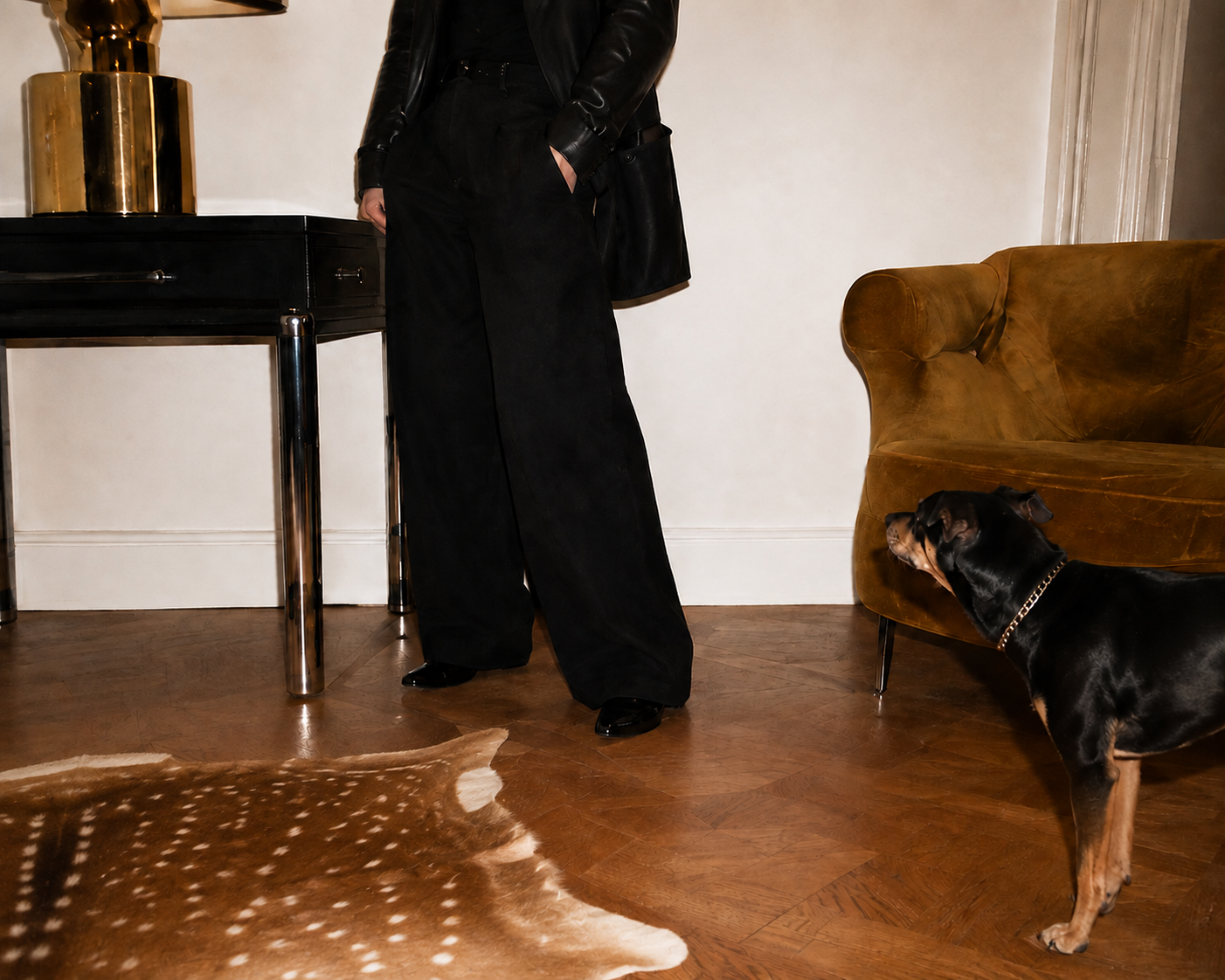 Veronica Lee Estes standing beside a black table and caramel velvet chair with Maddie, her dog, nearby.