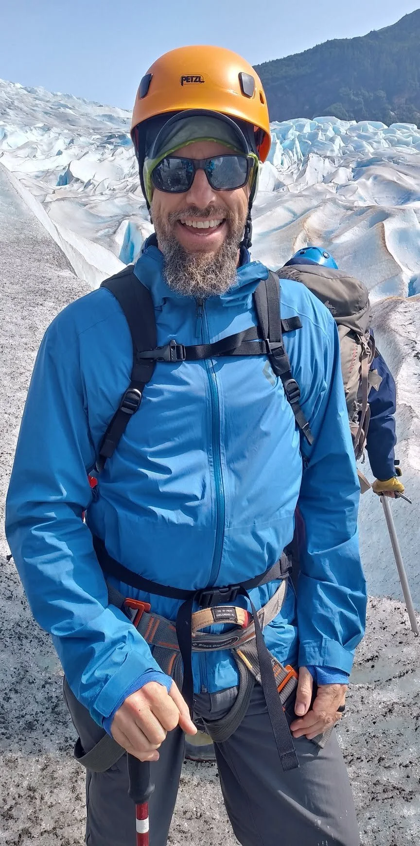 Man in outdoor mountaineering gear in snowy glacier landscape with mountains in the background.