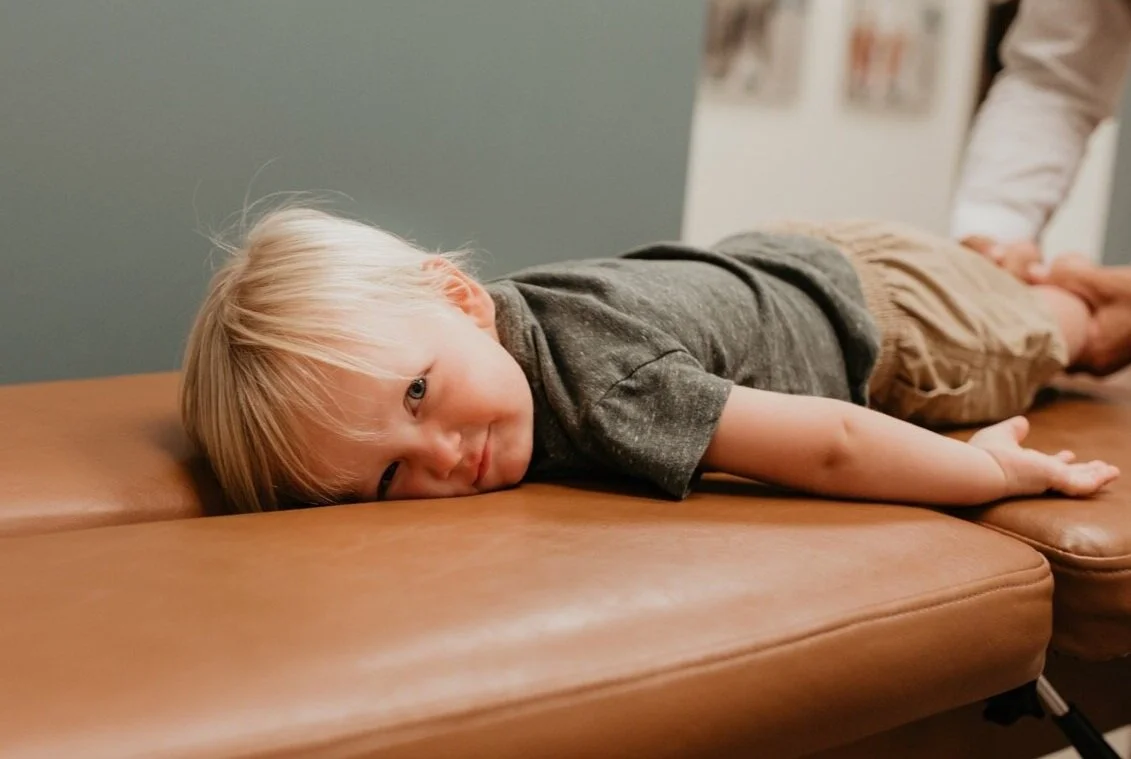 Toddler lying on chiropractic adjustment table.