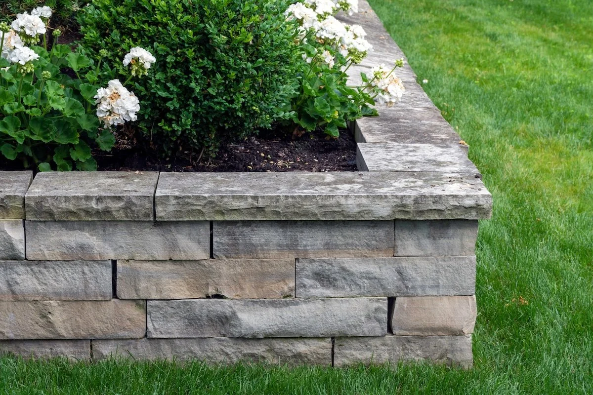 A natural stone retaining wall with matching coping