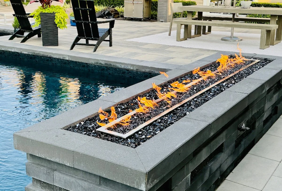 Luxury stone fire pit by inground pool and paver patio