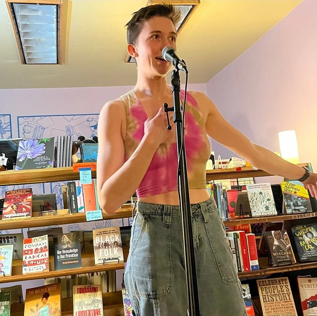 Elyssa in a pink shirt standing at a microphone