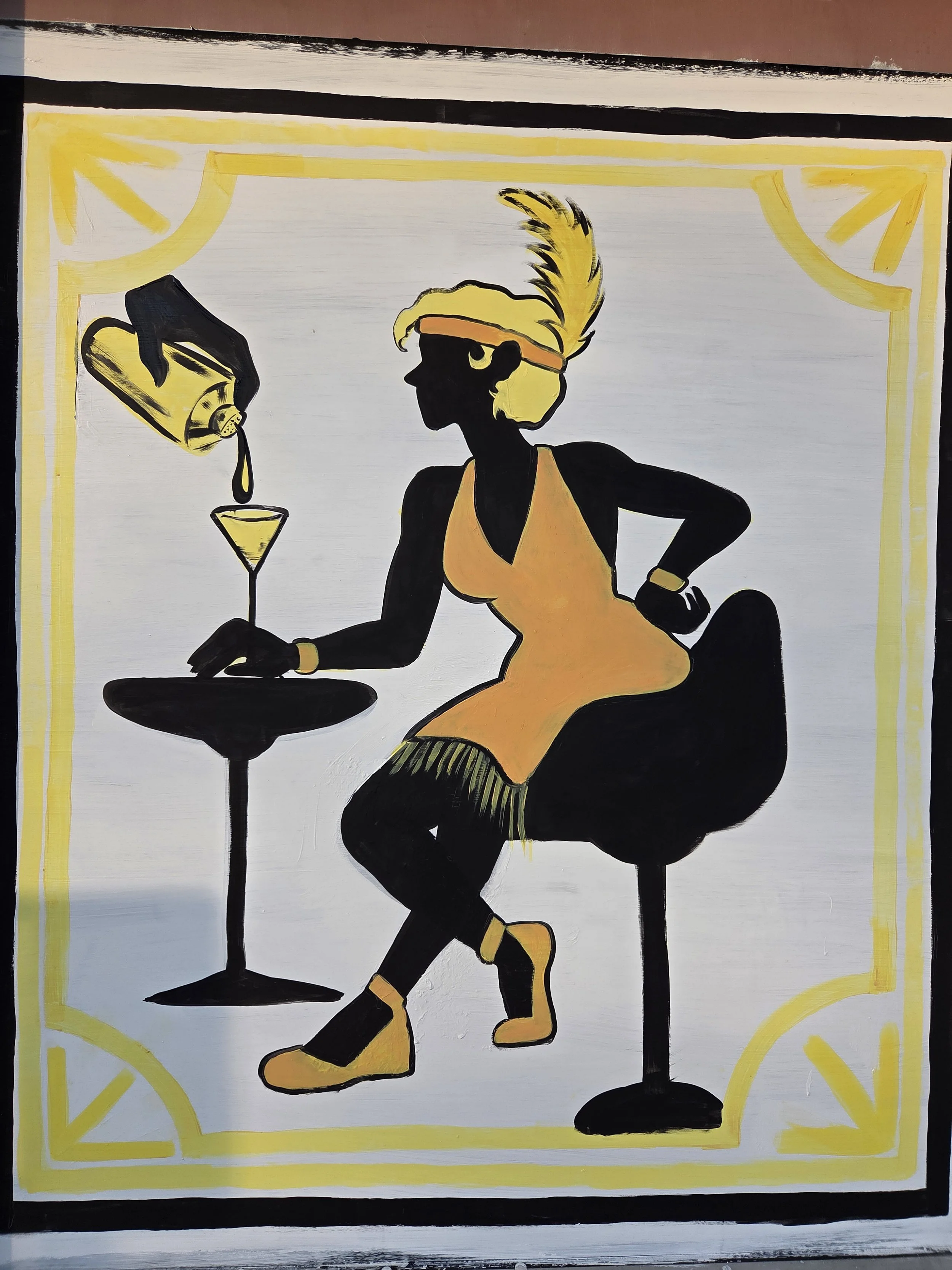 Silhouette of a woman with blonde hair and a feathered headband, sitting at a table with a martini and pouring a drink, depicted in a stylized, minimalist painting style with black, yellow, and orange colors.
