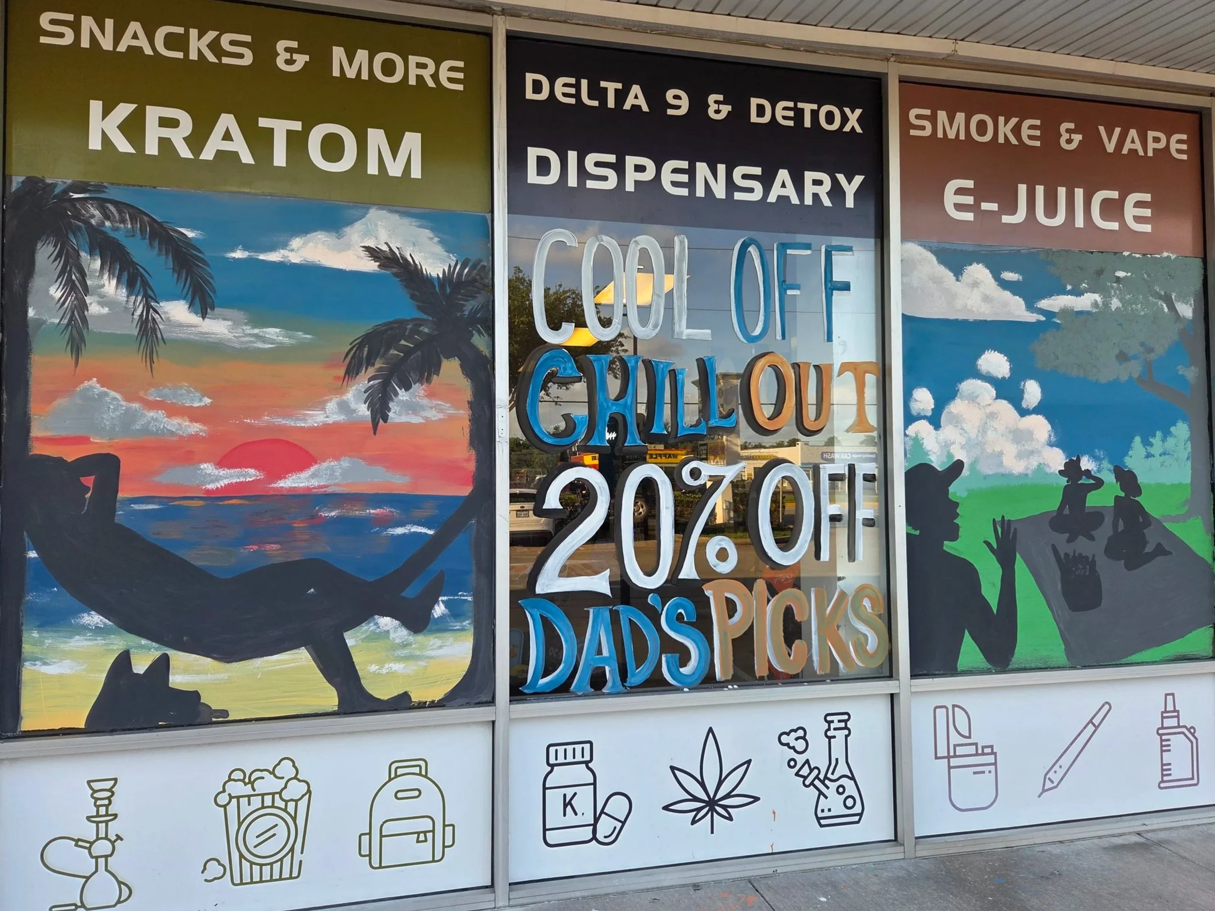 Storefront window displaying painted and neon signs advertising snacks, Kratom, Delta 9, detox, dispensary items, and e-juice. The window features a mural with a sunset, palm trees, and silhouettes of animals and people, along with icons of vaping and drug paraphernalia at the bottom.