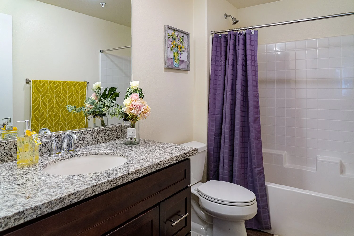 Spacious bathroom in Turtle Creek Apartment home with large vanity mirror, plenty of counter space, dark wood shaker cabinets and a shower/tub.