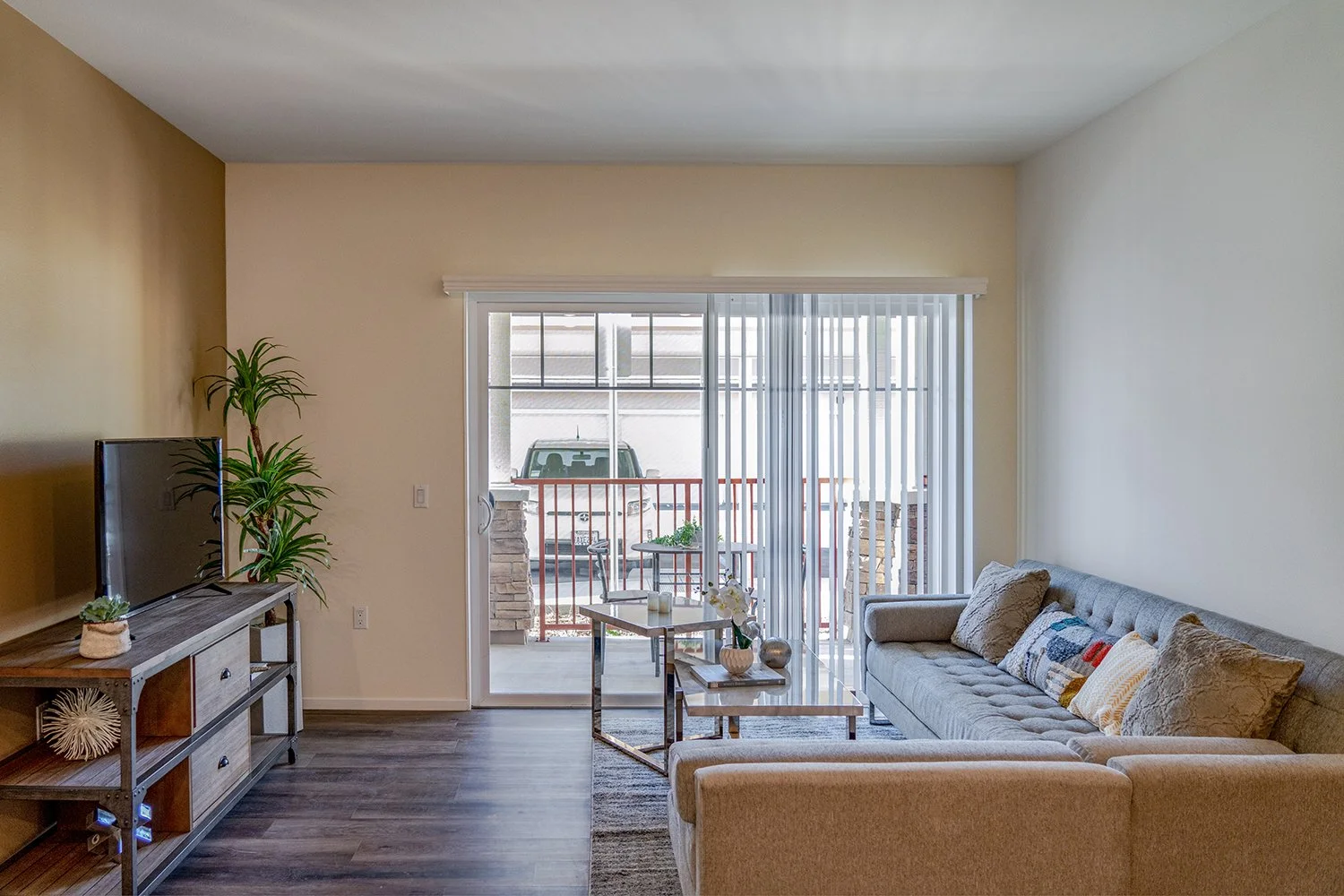 Living Area in Turtle Creek Apartment Home with wood-style plank flooring and large sliding doors leading to private patio. Open concept layout leads to dining nook and gorgeous updated kitchen.