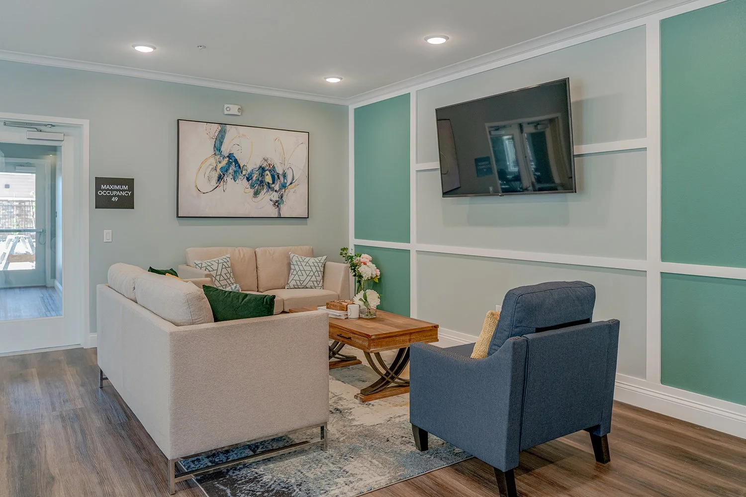 Lounge Area in Turtle Creek resident clubhouse with couch seating, a flat screen tv, a dining table and kitchen.  