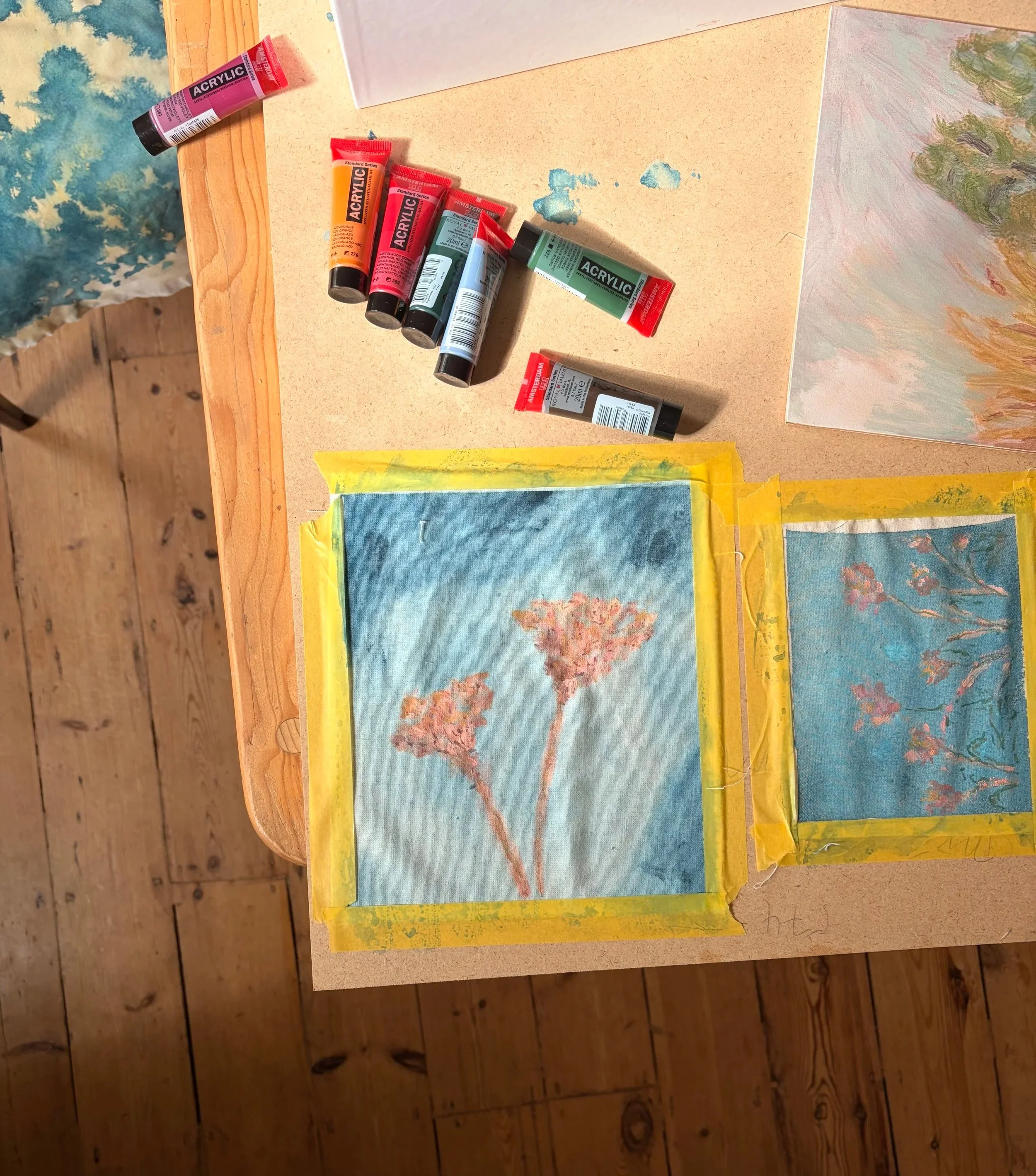A photograph of contemporary abstract botanical and floral paintings with paint tubes and tape