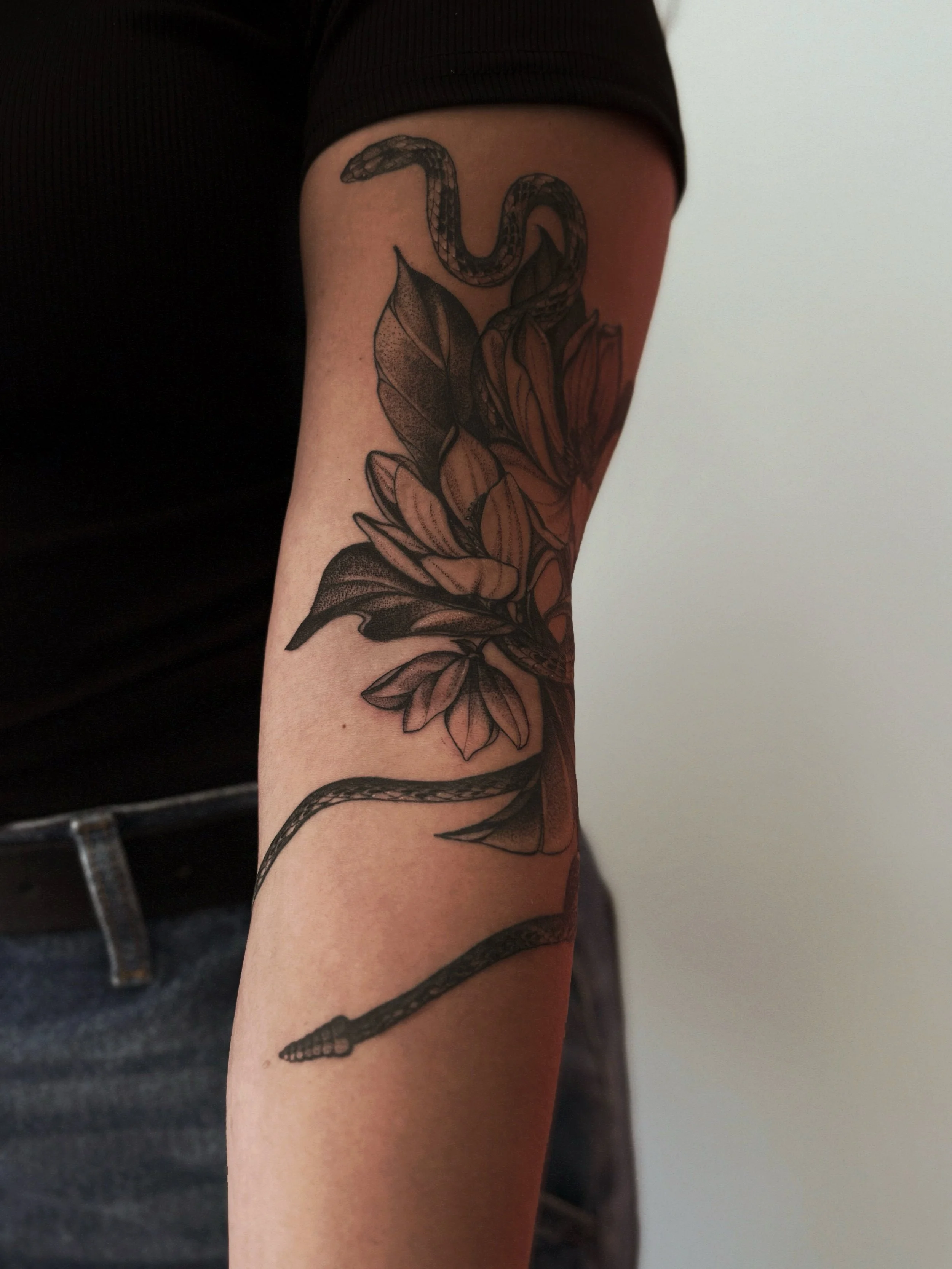 blackwork magnolia and rattlesnake wrapped around arm