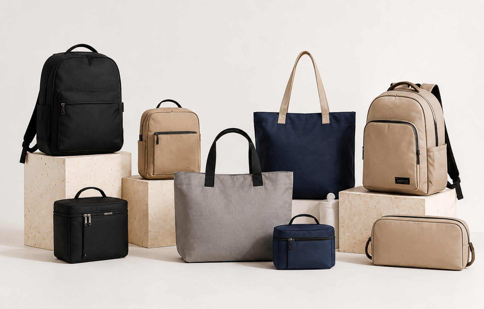 Variedad de bolsas y mochilas en tonos neutros y oscuros, colocadas sobre pedestales de piedra en un fondo blanco.