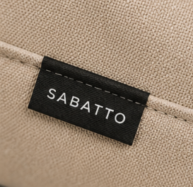 Etiqueta de tela con la marca 'SABATTO' en una bolsa de color beige