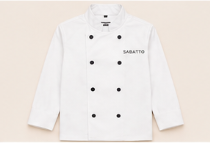 Chaqueta de chef blanca con botones negros y la palabra 'SABATTIO' impresa en el pecho izquierdo.