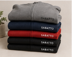 Cuatro sudaderas apiladas en colores gris, azul, rojo y negro, todas con la palabra 'SABATTO' en la parte inferior derecha.