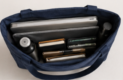 Una bolsa azul con artículos escolares, incluyendo una laptop, varios bolígrafos y rotuladores, y otros objetos.