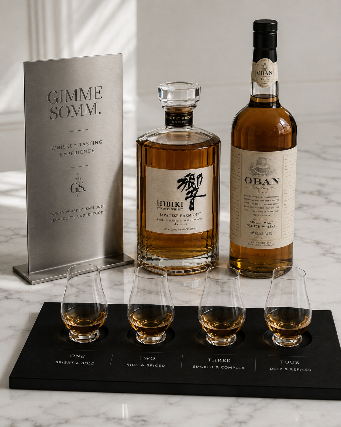 Two bottles of whiskey, one Hibiki Japanese Harmony and one Oban single malt scotch, are placed on a marble surface with a whiskey tasting flight in front. The flight consists of four glasses with different descriptions: Bright & Bold, Rich & Spiced, Smoked & Complex, and Deep & Refined. A metal sign explains that good whiskey isn't just served, it's understood.