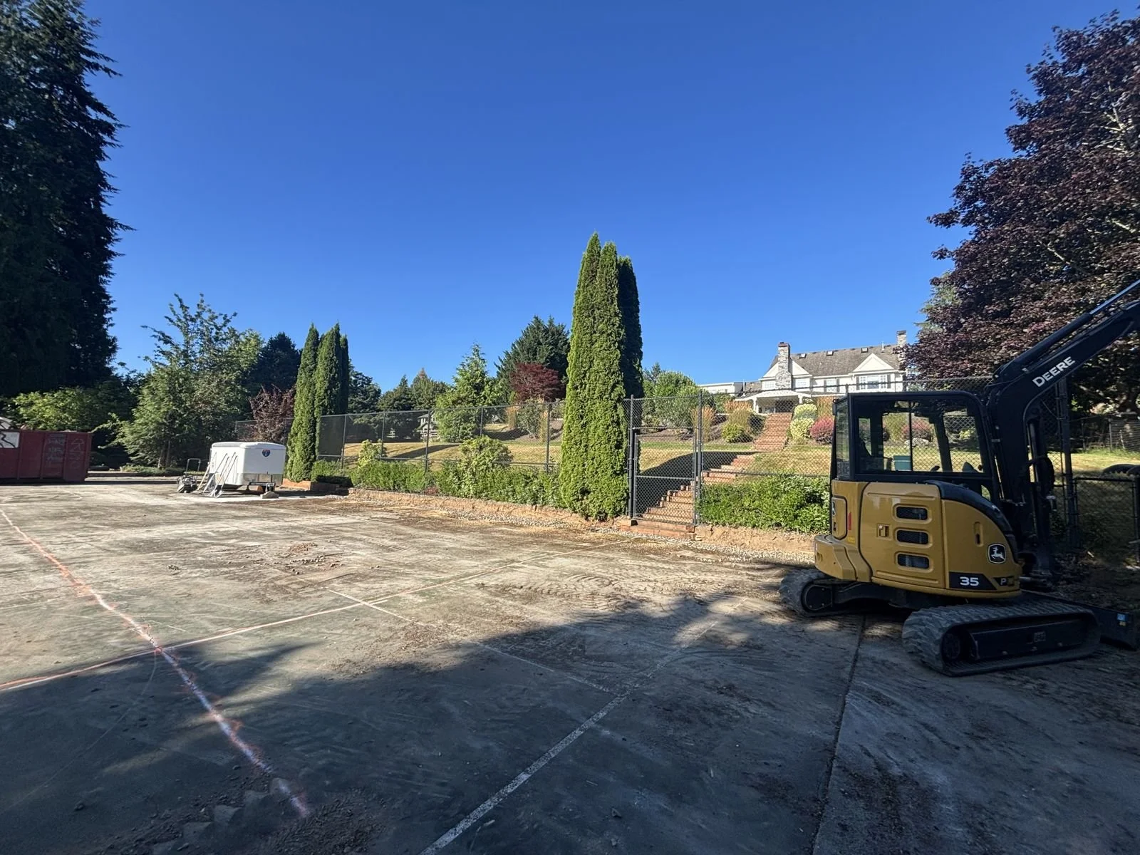 Mini excavator on old sport court during demolition in Snohomish WA