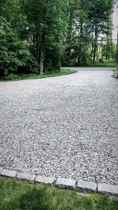 Gravel driveway surrounded by green grass and trees.
