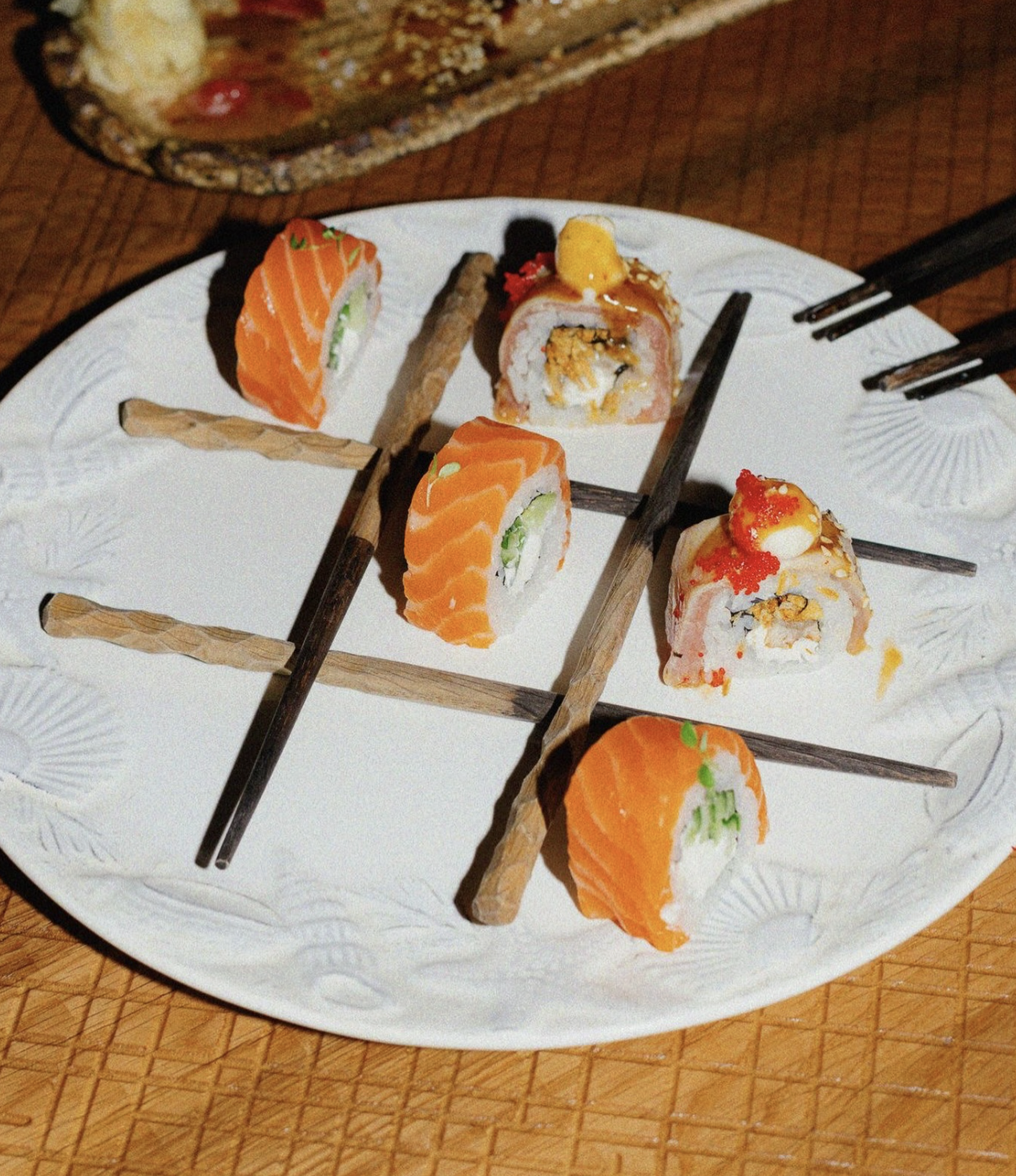 Assorted sushi rolls with salmon, avocado, and various toppings on a white decorative plate.