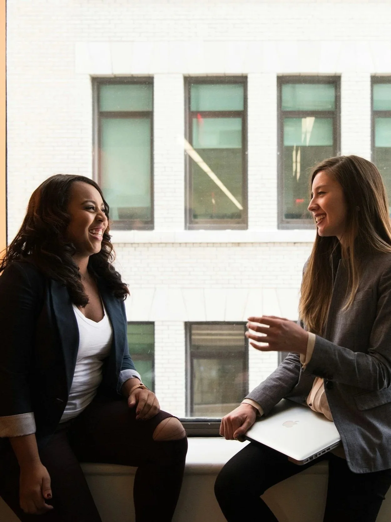 Two professional women talking during a meeting.