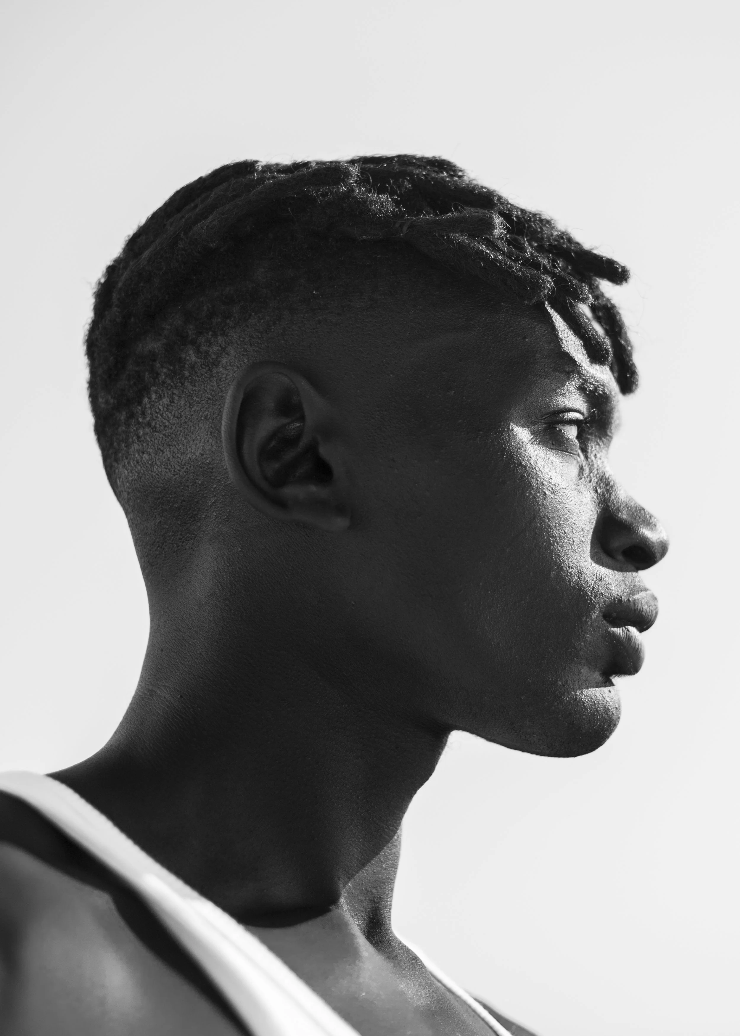Profile of a young African American woman with short dreadlocks, looking to the right, in black and white.
