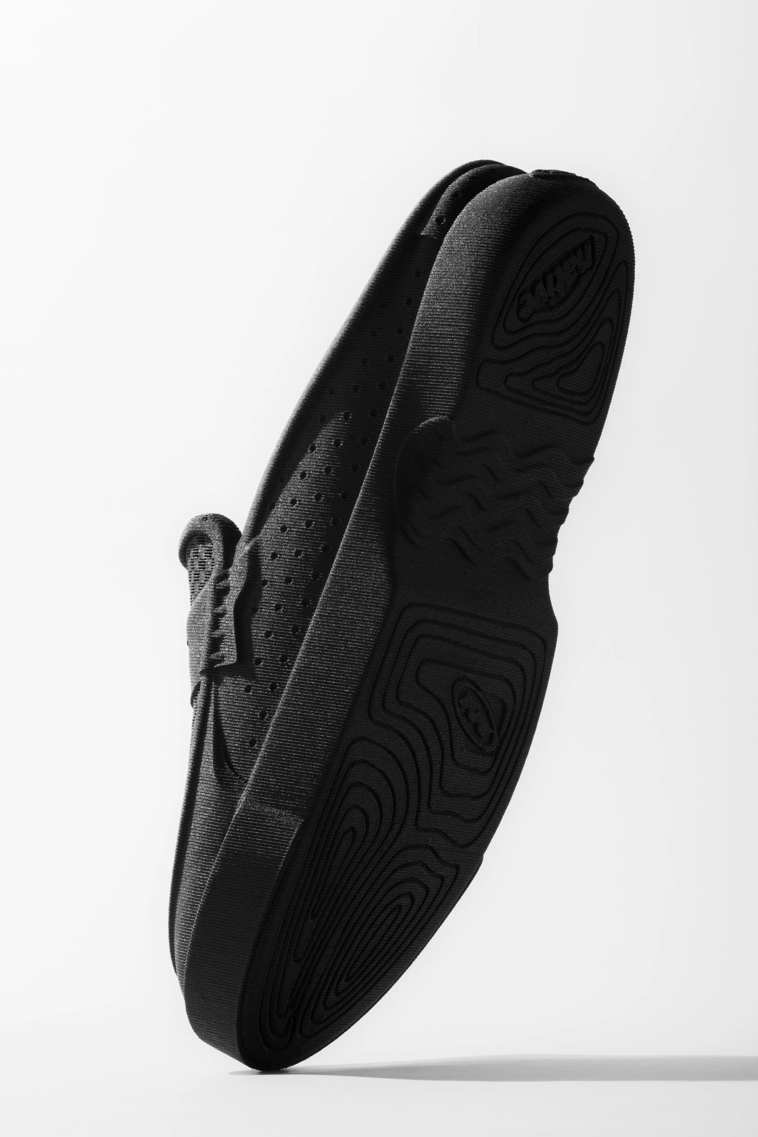 Black platform shoe with a thick sole and textured pattern, isolated on a white background.
